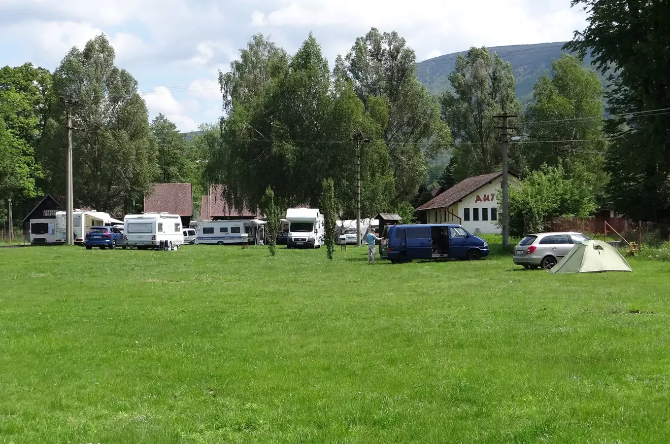 Autokemp v Hejnicích s karavany a stany na trávníku.