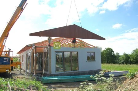 Montáž střechy na prefabrikovaný dřevěný dům pomocí kranu.