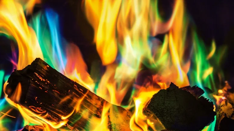 Zapálené dřevo s barevnými plameny v krbu nebo kotli.