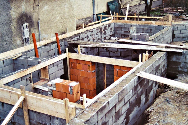 Základy budovy z bloků v jámě s dřevěným oporovým systémem.