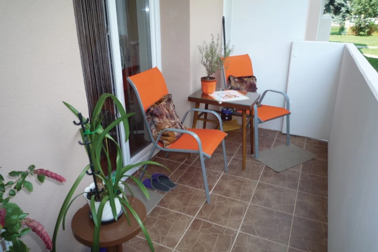 Přestavěná lodžie s oranžovými židlemi, stoly a rostlinami.