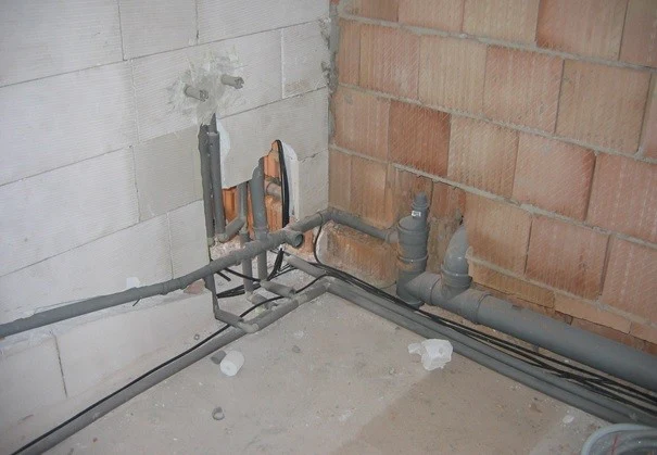 Systém vodovodních i odpadních potrubí v koupelně během instalace.