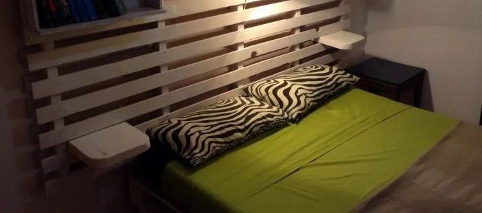 Postel s hlavou z dřevěných palet v ložnici.