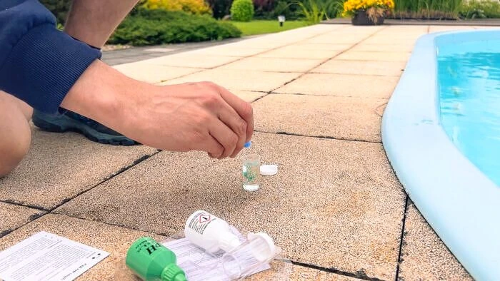 Muž zkouší chemii vody v bazénu pomocí kapalin pro údržbu.