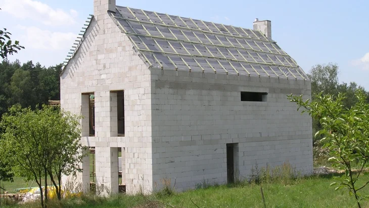 Částečně postavený dům z porobetonu na pozadí zelené přírody.