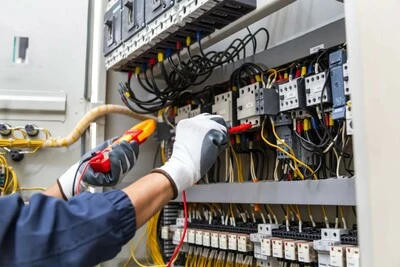 Elektrikář měří napětí v rozvaděči pomocí multimetru.