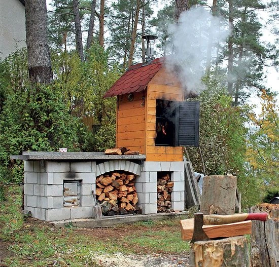 Samostatně postavená dřevěná udírny s kamenným podstavcem pro dřevo a kouřem.