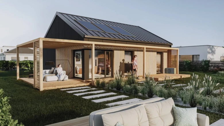 Moderní prefabrikovaný dřevěný dům s solárními panely na střeše a venkovním posezením.