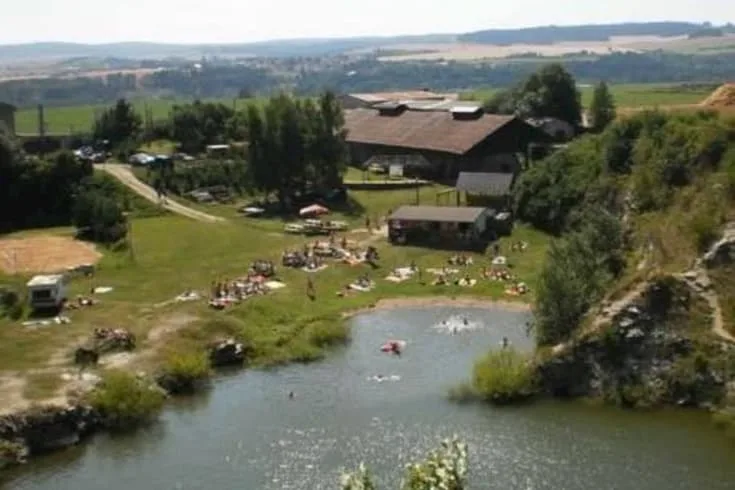 Kemp s rybníkem a velkými budovami pro ubytování na Vysočině.