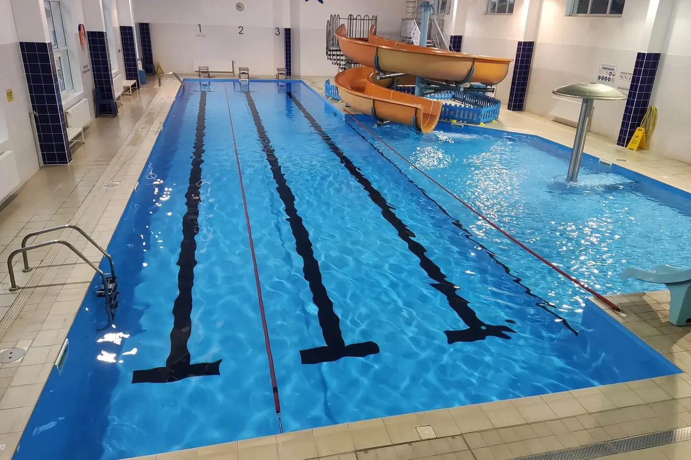 Vnitřní bazén s dráhy pro plavání a vodními skluzavkami.