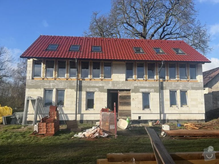 Dům v hrubé stavbě s červenou střechou a okny.