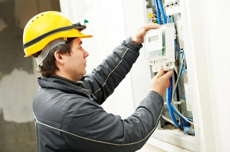 Elektrikář zapojuje rozvaděč s modrými vodiči.