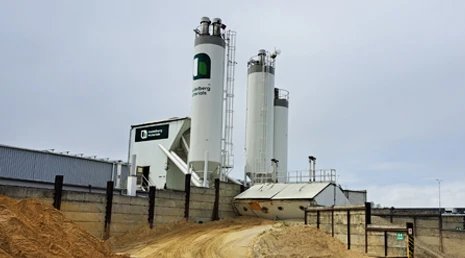 Fotografie průmyslové betonárny s vysokými nádržemi pro výrobu betonu.