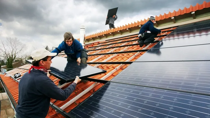 Montáž fotovoltaických panelů na střechu domu.