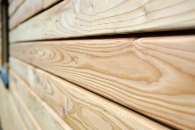 Detail dřevěné fasády s přírodním vzorem kovu.