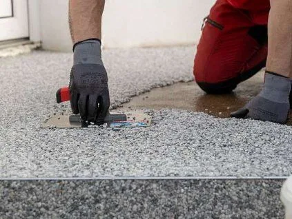 Pracovník nanáší epoxidovou stěrku na beton pomocí špachtle.