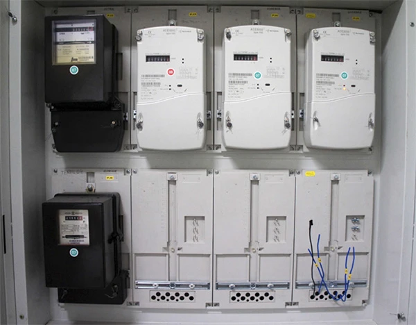 Elektrický rozvaděč s elektroměry a jističi v šedém skříni.