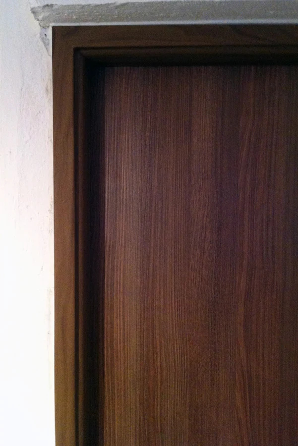 Detail tmavého dřevěného zárubně s viditelnou kresbou dřeva.