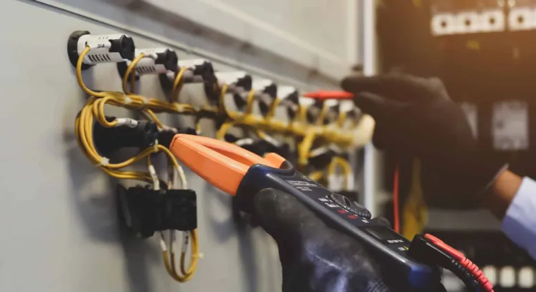 Elektrotechnik měří napětí v rozvaděči pomocí multimetru.