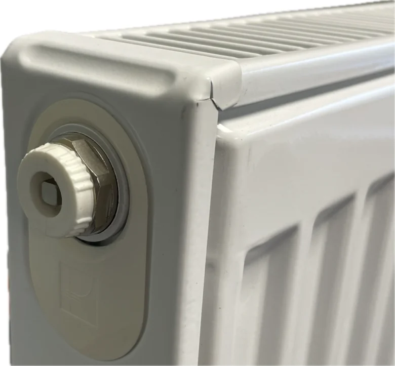 Bílý radiátor s plastovým odvzdušňovacím ventilom pro topení.
