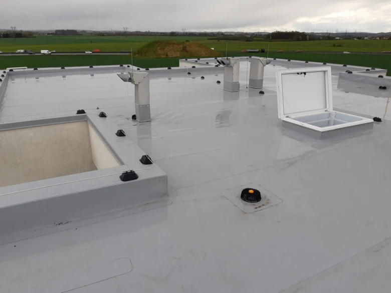 Detailní pohled na atiku střechy s hydroizolací a větracími prvky.