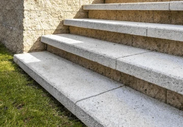 Betonové venkovní schody vedoucí k zdi na trávníku.