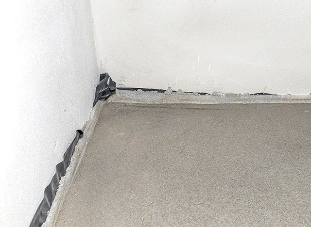 Detailní pohled na dilatační spáru v rohu podlahy.