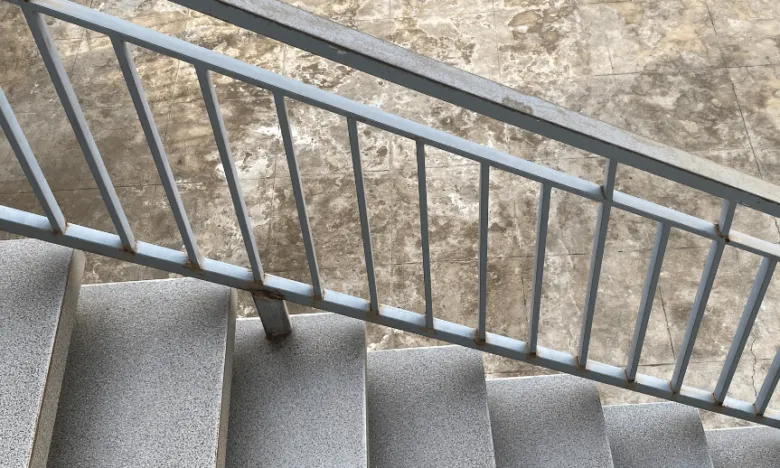 Světlé schodiště s kovovým zábradlím zespodu nahoru.