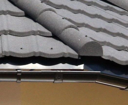Detail střechy s okapnicí a šindelem.