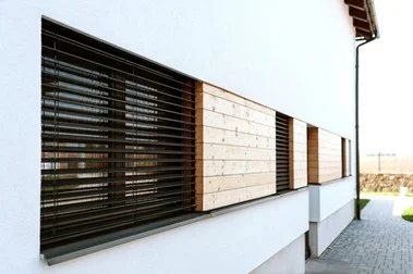 Venkovní žaluzie na fasádě domu s dřevěnými panely.