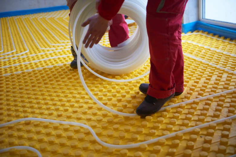 Instalace podlahového topení s rozvodem potrubí na žluté vrstvě.