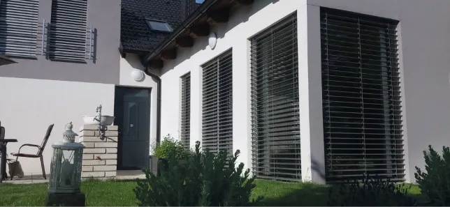 Venkovní žaluzie namontované na fasádu bílého domu.