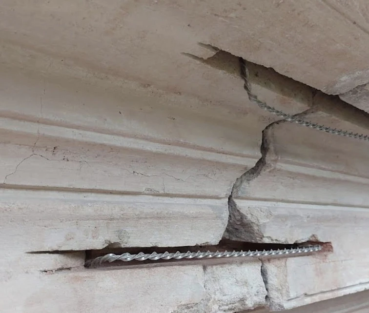 Helikální výztuž viditelná v prasklém kamenném nebo betonovém prvku.
