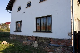 Bílý dům s odhaleným základem a hydroizolací zdiva.