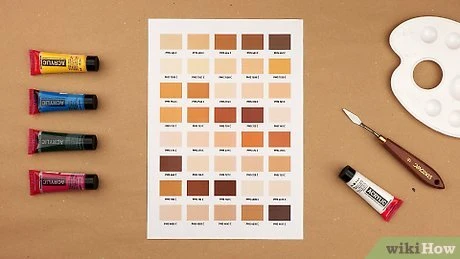 Paleta s barvami pro míchání hnědé barvy na dřevěném povrchu.