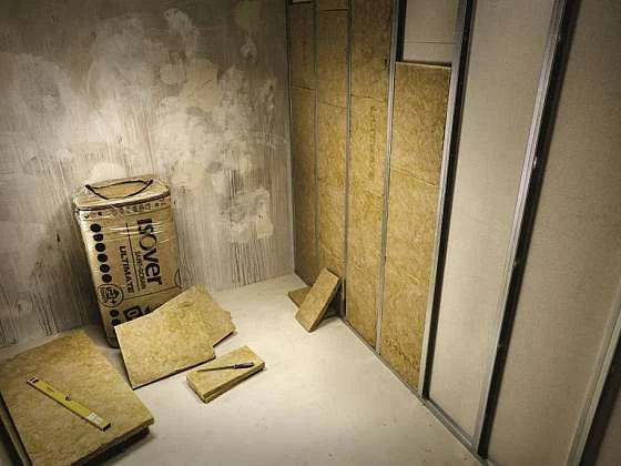 Práce na sádrokartonu: izolační desky, maltový kbelík a kovové profily.