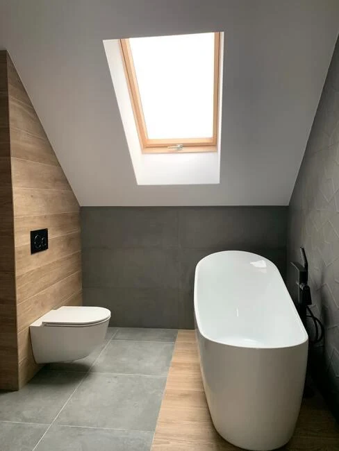 Moderní malá koupelna s vanou pod střešním oknem.