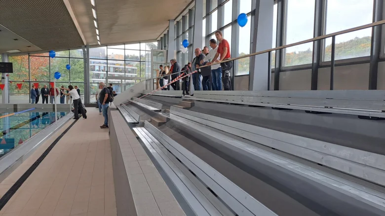 Vnitřní plavecký bazén s diváky na tribunách.