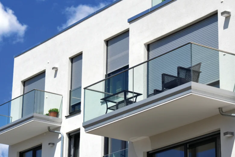 Moderní dům s venkovními roletami na balkóně a oknech.