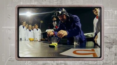 Muž v ochranném obleku testuje elektrický zkrat před studenty.