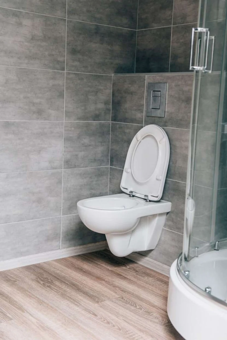Zdvižená bílá zdi připevněná toaleta s funkcí bidet v moderním koupelnovém interiéru.