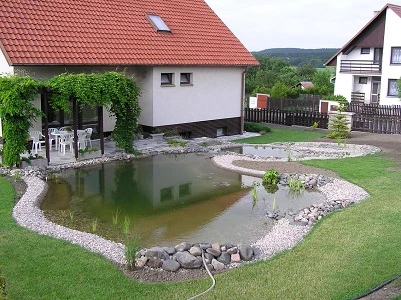 Zakončené koupací jezírko s kamenným obvodem v zahradě.