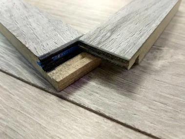 Detail spoje laminátových podlahovky s viditelnou vnitřní strukturou.