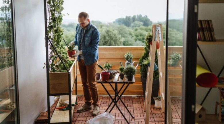 Muž s rostlinami na malém balkóně v paneláku