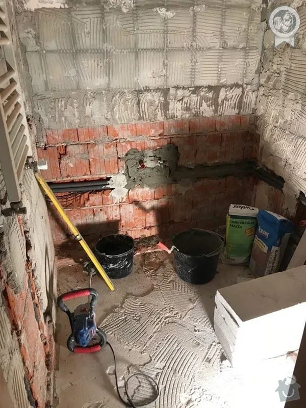 Koupelna v rekonstrukci s omítkou na zdi a nástroji.