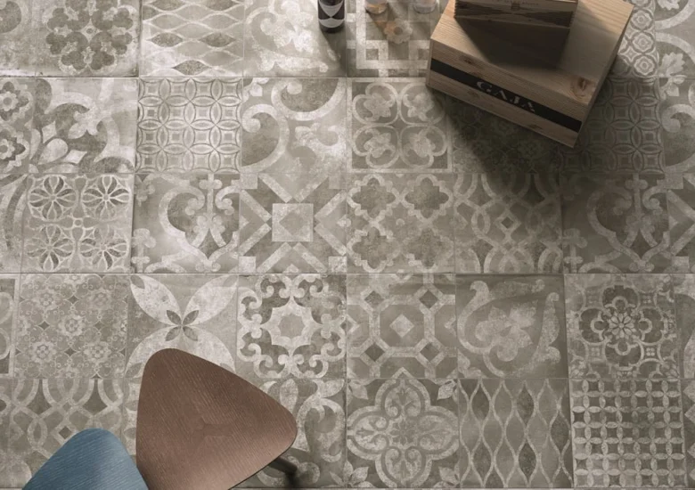 Různé šedé dlaždice s ornamenty na podlaze v interiéru.