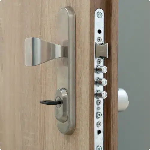 Detailní pohled na bezpečnostní zámek s klíčem v kování dřevěných dveří pro výměnu.