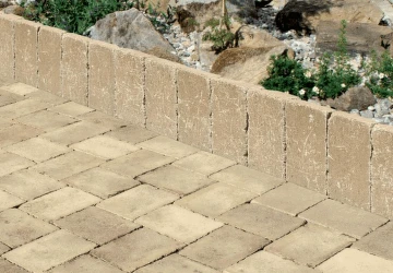 Pohled na betonové obrubníky a dlažbu v zahradním prostředí.