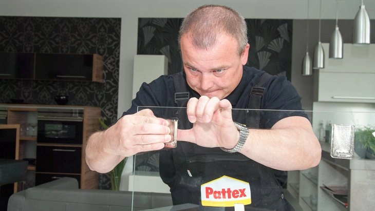 Muž lepi sklo akrylátovým lepidlem značky Pattex.