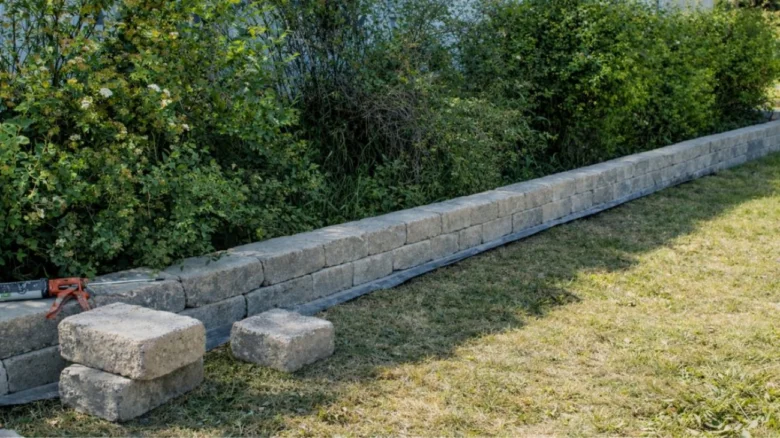 Stavba opěrné zdi ze žulových bloků s nástrojem na místě.